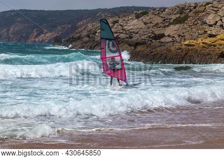Guincho, Portugal - July 11, 2021: a surfer riding the wave during a sunny day on the blue ocean sea of Guincho, Portugal.