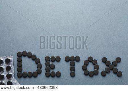 Word Detox Made Of Activated Charcoal Pills Near Blisters On Grey Background, Flat Lay With Space Fo