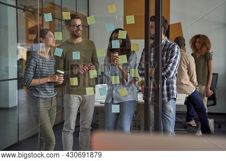 Succesful Team. Group Of Happy Business People, Coworkers Looking At Sticky Notes On A Glass Board, 
