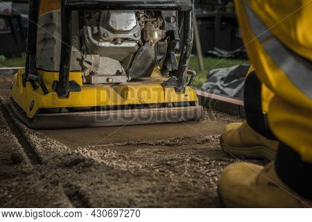 Professional Soil Compactor Job Close Up. Building Concrete Tiles Garden And Patio Pathway. Powerful