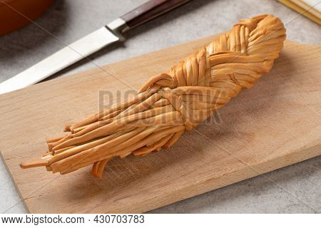 Smoked braided cheese, called Chechil, from the Adyghe Republic on a cutting board close up