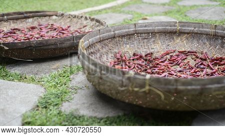 Red Chili Peppers Drying Out In The Sun Naturally, Laying Flat, And Spreads Thin Out On Mat Baskets 