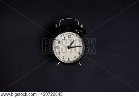 High Angle View Of A Monochrome Composition With A Vintage Alarm Clock On Black Background With Copy