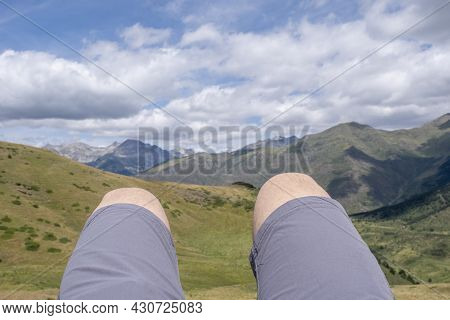 Close Up Of The Legs Of A Mountaineer Lying On A Peak With The Mountains Out Of Focus In The Backgro