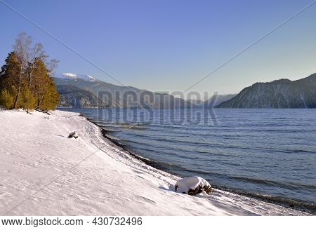 The Winding Shore Of The Teletskoye Lake, Which Does Not Freeze In Winter. Blue Water And Sky On A S