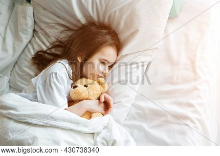 Baby Lying In Bed With Taddy Bear. Little Girl Sleeps With Knitted Toy