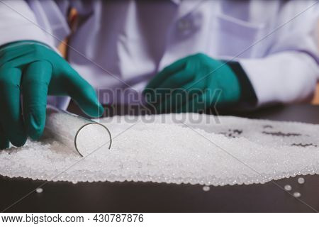 Man Hands Wearing Gloves Hold Polymer Pallet. Plastic Beads On Green Gloved Hand. Polymer Beads. The