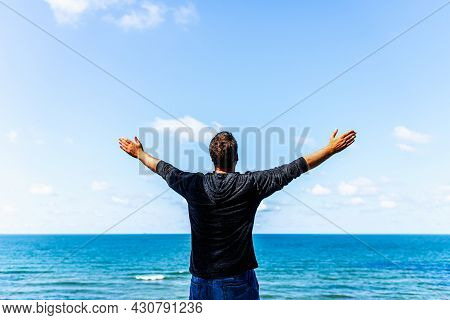 Caucasian Man Spreading Arms And Watching The Ocean. Happy Man With Outstretched Arms.man With His A