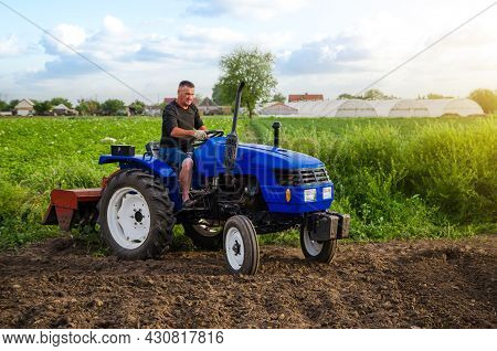 Farmer On A Tractor Works In The Field. Land Cultivation. Seasonal Worker. Recruiting And Hiring Emp