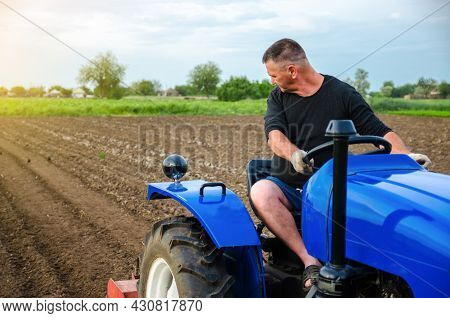 A Farmer On A Tractor Works In The Field. Freeing Milling Earth Ground From Old Crops. Land Cultivat