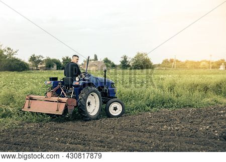 A Farmer Is Driving A Tractor Across The Field. Mill Grinding Machine For Soil. Land Cultivation. Re