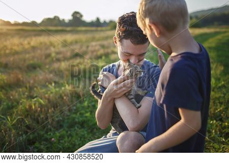 Young Guy Found And Picked Up Little Stripped Kitten During Walking In The Field And Going To Home I
