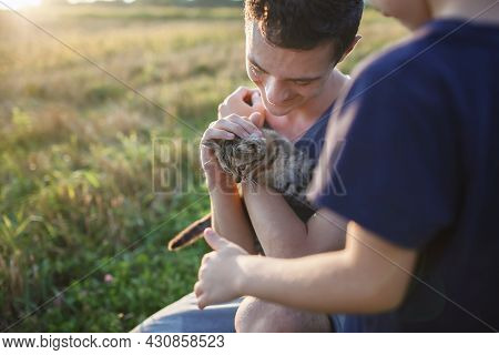 Young Guy Found And Picked Up Little Stripped Kitten During Walking In The Field And Going To Home I