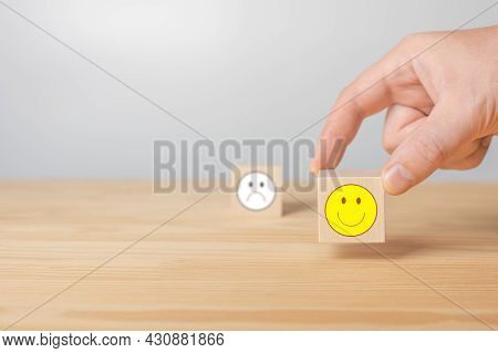 Man Points His Finger At A Wooden Cube With Positive Face. Cube With Sign Of Negative Face Icon Is B