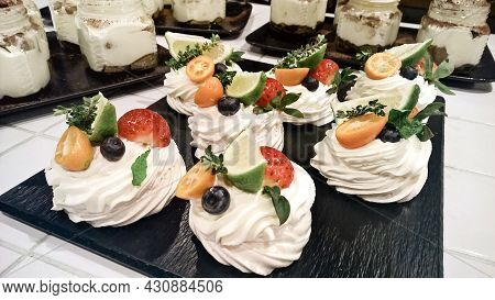 Anna Pavlova Desserts On A Black Plate And Jars Of Tirramissu On Background. Australian Cuisine Conf