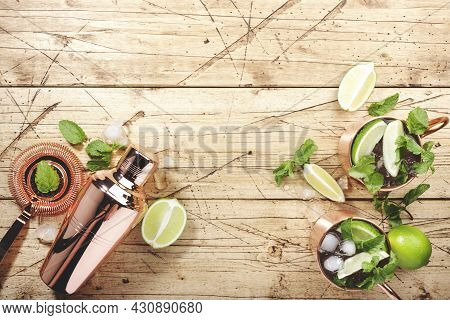 Moscow Mule Cocktails In Copper Mug With Lime, Ice, Ginger Beer, Vodka And Mint. Wooden Background, 