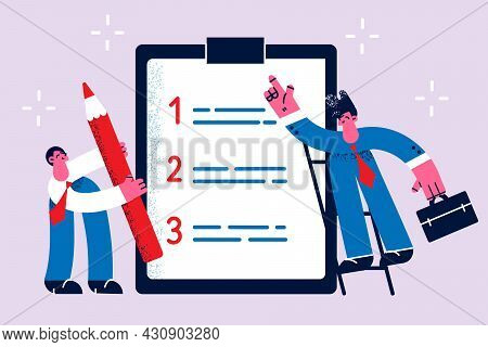 Time Management And List Of Tasks Concept. Two Business People Standing Around Huge List Of Work Dut