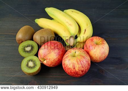 Assorted Fresh Ripe Fruits On Black Wooden Background With Cut Kiwifruit For The Concept Of Eating W