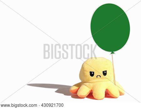 Yellow Angry Toy Octopus With Green Balloon Isolated On White Background. Sad Or Moody Kids Concept.