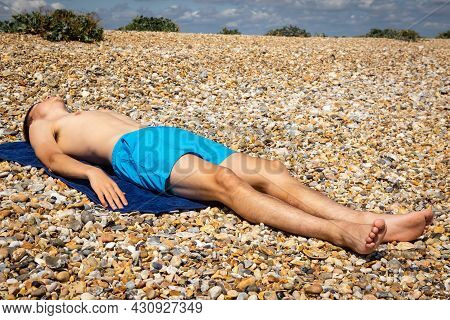 A 18 Year Old Caucasian Shirtless Teenage Boy Sunbathing On A Stoney Beach