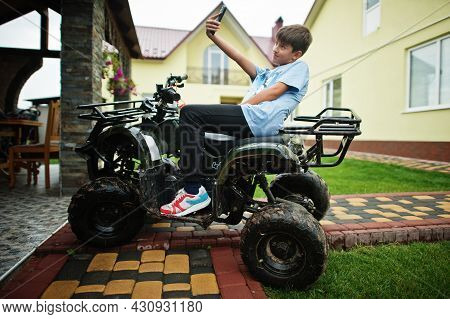 Boy In Four-wheller Atv Quad Bike With Mobile Phone.