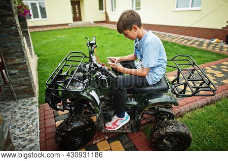 Boy In Four-wheller Atv Quad Bike With Mobile Phone.