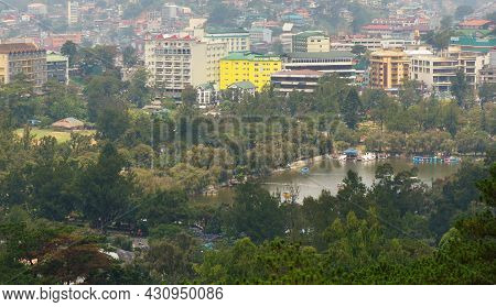 Lake, Trees And Commercial Buildings In Baguio City. A City Located In A Mountainous Area In The Phi