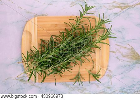 Branches Of Fresh Rosemary On A Wooden Board. View From Above.