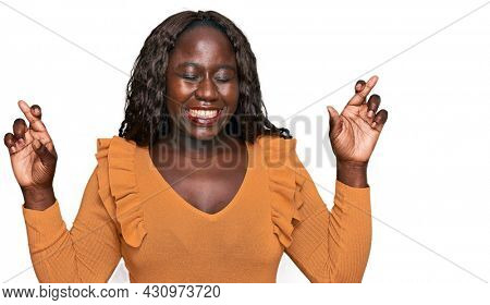 Young african woman wearing casual clothes gesturing finger crossed smiling with hope and eyes closed. luck and superstitious concept. 