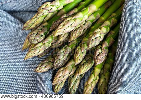 Close-up Detail Bunch Of Fresh Raw Green Asparagus Plant Harvested At Season On Blue Rustic Fabric K