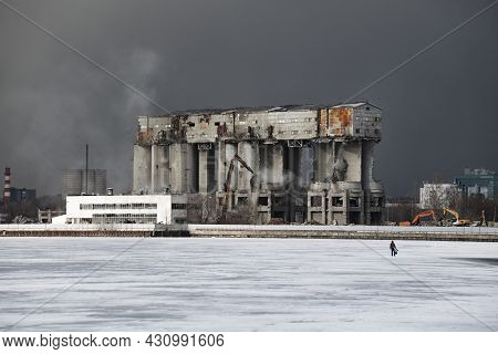 An Industrial Building Is Under Deconstruction, A Fisherman Is Walking On Ice, A Snowstorm Is Coming