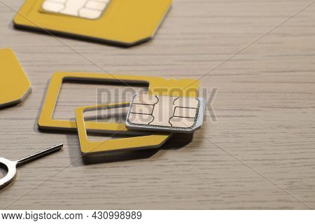 Different Sim Cards And Ejector On Wooden Background, Closeup