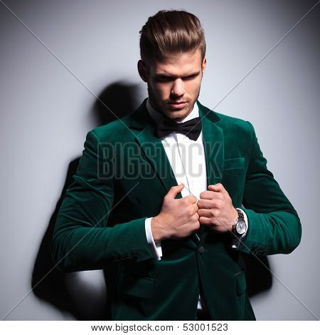 young man in green suit and bow tie looking a little sad on gray background