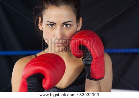 Close-up portrait of a beautiful young woman in red boxing gloves in the ring