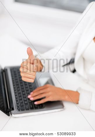 office, business, technology and internet concept - businesswoman with laptop computer showing thumbs up