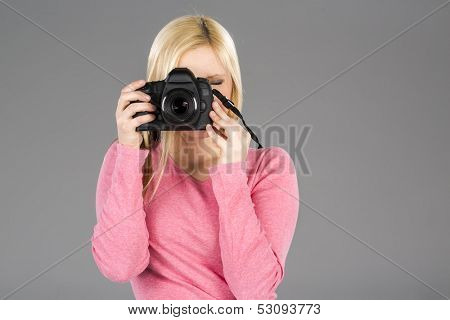 Blonde model holding a camera in a studio environment