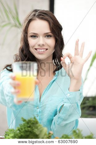 health and beauty concept - woman holding glass of orange juice and showing ok sign