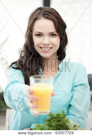 health and beauty concept - young woman holding glass of orange juice