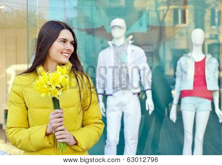 Portrait of young beautiful woman with spring flowers, outdoor over shopwindow with dummy.