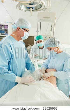 Team of surgeon in uniform perform varicose veins correction operation on a patient at surgery clinic