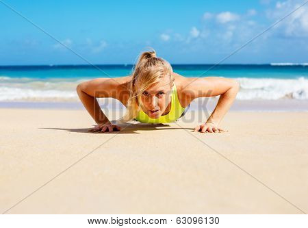 Young attractive woman doing push ups outside. Fitness woman working out at the beach.  Fitness Concept.