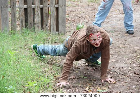 MUSKOGEE, OK - Sept. 13: A very flexible actor terrifies athletes as a bloody zombie during the Castle Zombie Run at the Castle of Muskogee in Muskogee, OK on September 13, 2014. 