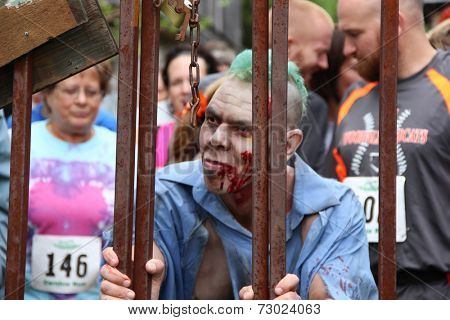 MUSKOGEE, OK - Sept. 13: A bloody zombie stands behind a fence, ready to hunt for runners during the Castle Zombie Run at the Castle of Muskogee in Muskogee, OK on September 13, 2014. 