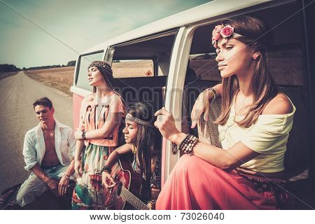 Multi-ethnic hippie friends with guitar on a road trip
