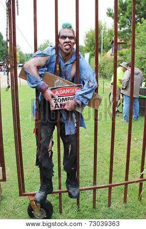 MUSKOGEE, OK - Sept. 13: A bloody zombie holds a metal fence, ready to chase his victims during the Castle Zombie Run at the Castle of Muskogee in Muskogee, OK on September 13, 2014. 