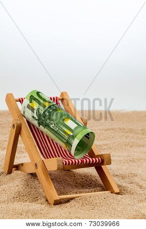 a deck chair with a euro banknote. symbol photo for saving on holiday and when traveling