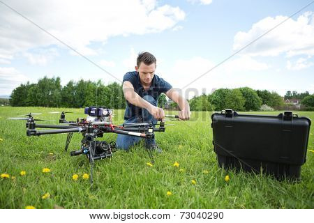 Young technician fixing propeller of UAV helicopter with handtool in park