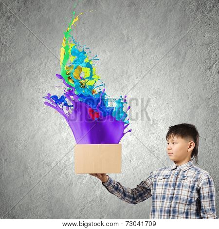 Young boy splashing colorful paint from carton box
