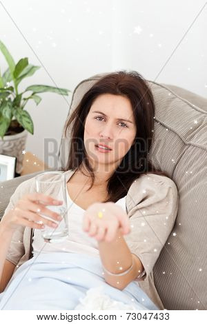 Sick woman showing a pill to the camera with twinkling stars