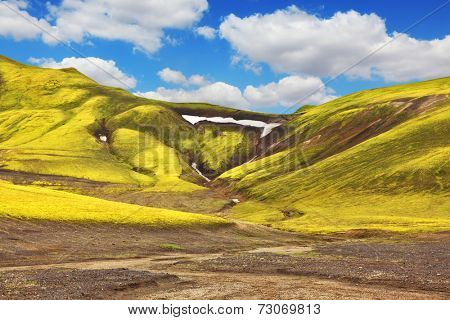  Green moss on smooth slopes and white spots snowfields in the gullies. Magnificent colorful mountains. Reserve Landmannalaugar, Iceland